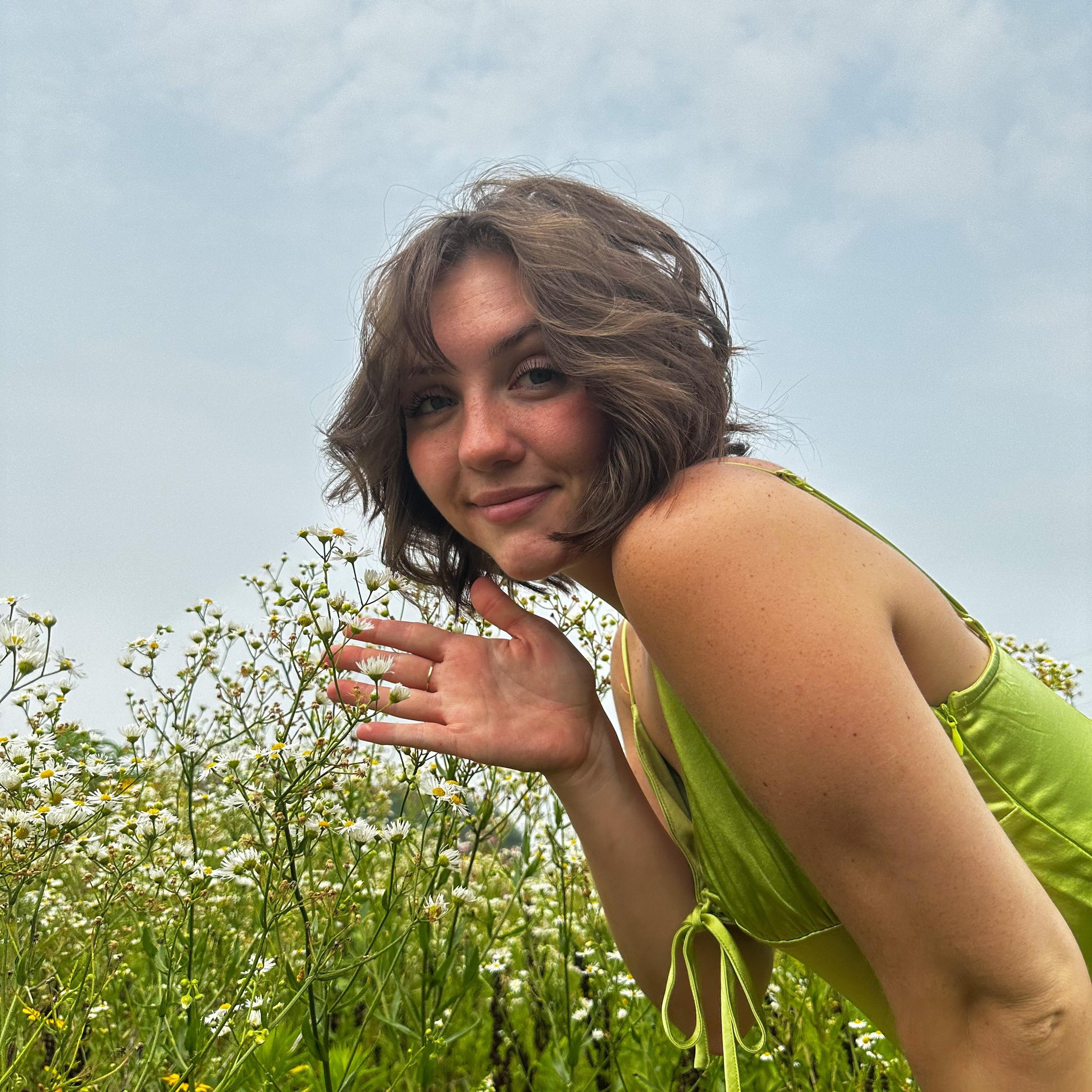 Rae smiling in a field of wildflowers